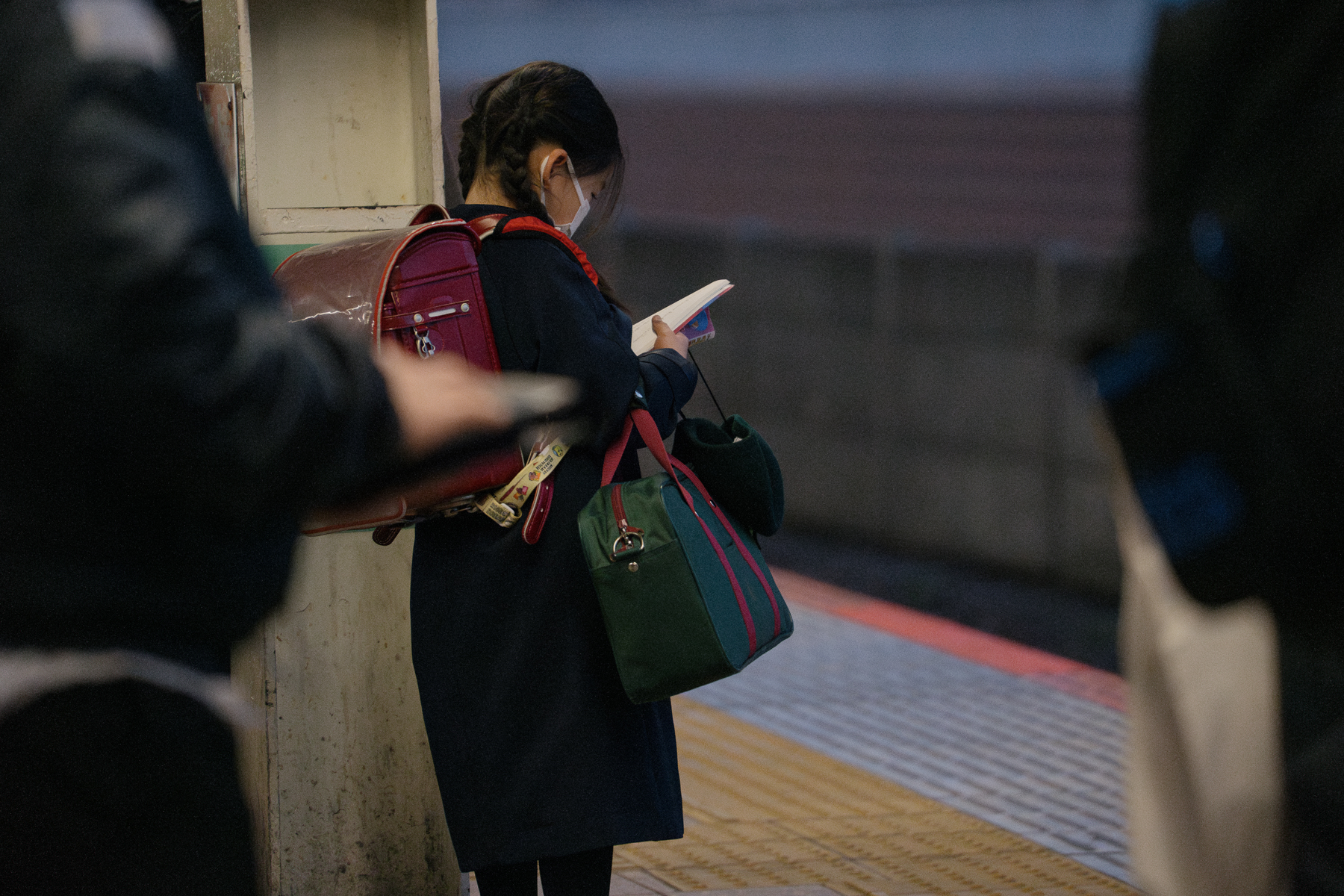 <span style="color: rgb(0, 0, 0);">An elementary school student studying on the train platform while waiting for her train.</span>