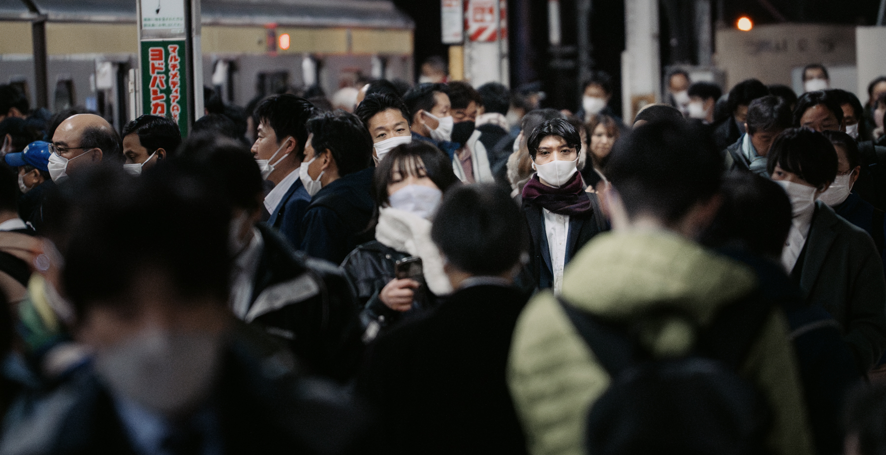 A man with a tense facial expression on a crowded train platform.