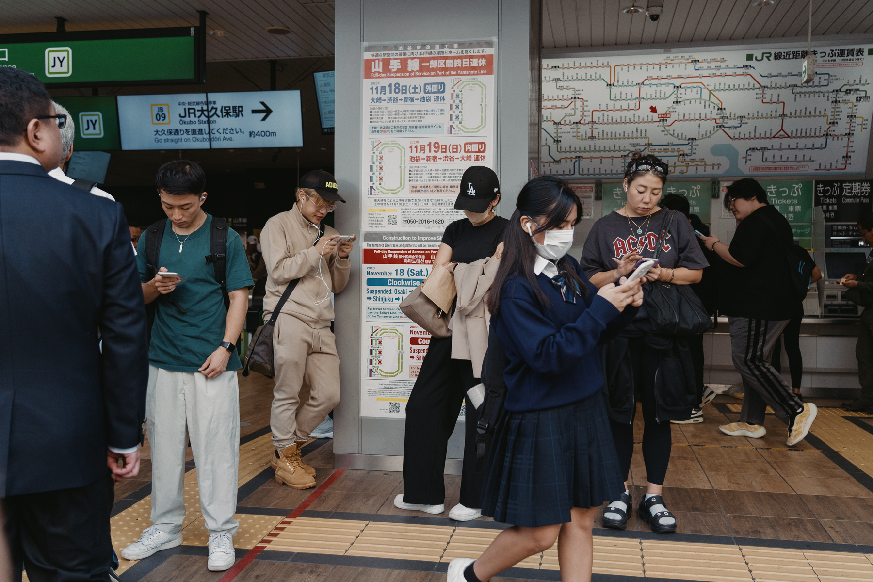 <span style="color: rgb(0, 0, 0);">People at a train station. All except one are on their phones.</span>