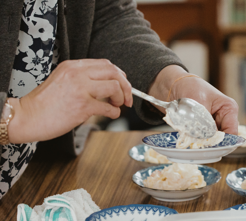 A woman's hands scooping out potato salad at church.
